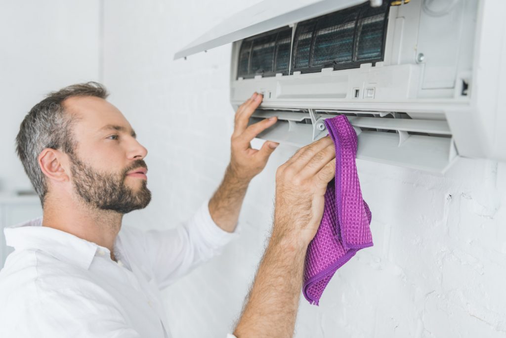 bearded-man-cleaning-air-conditioner-with-rag.jpg
